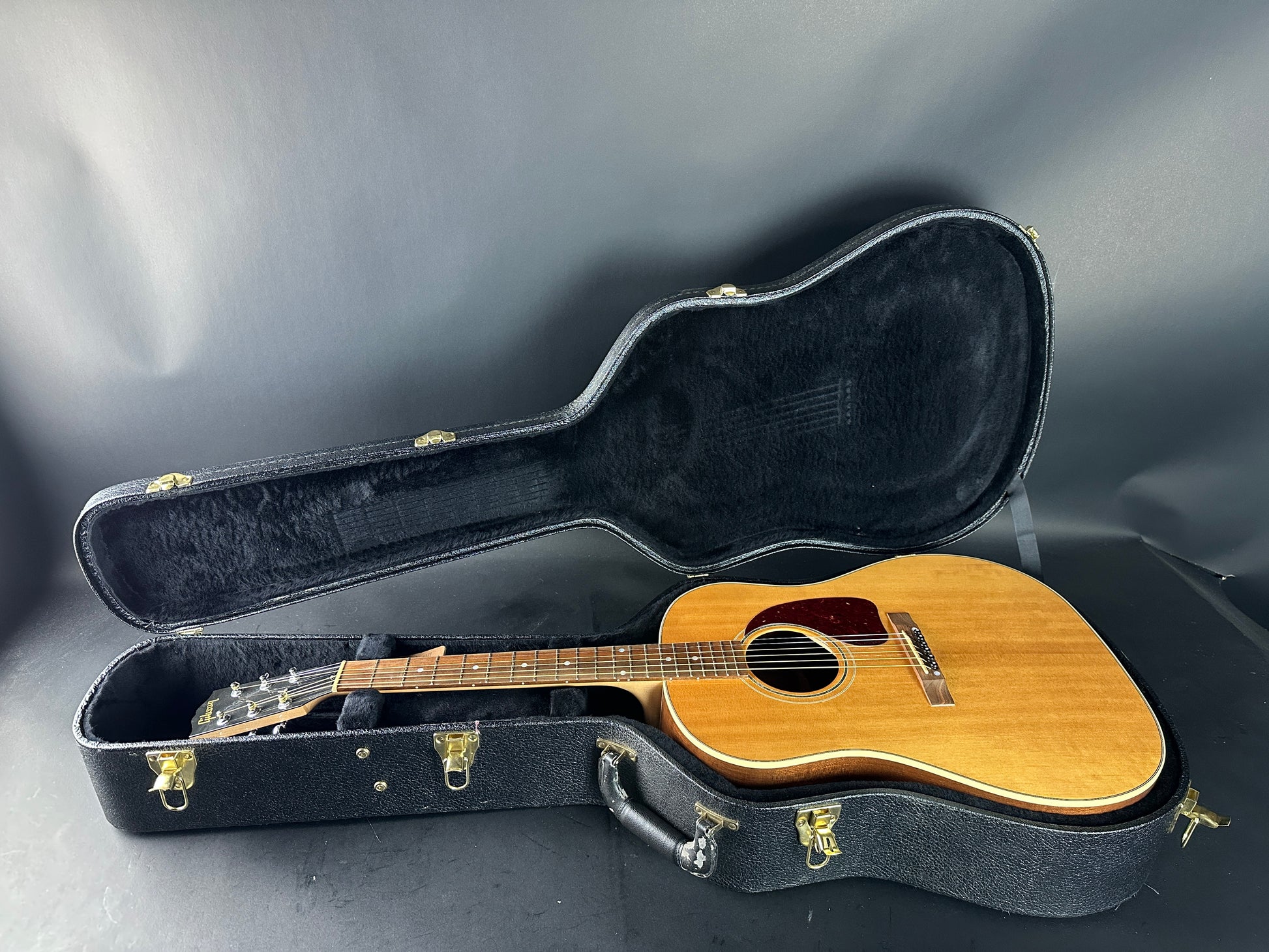 Acoustic guitar in a black case on a gray background