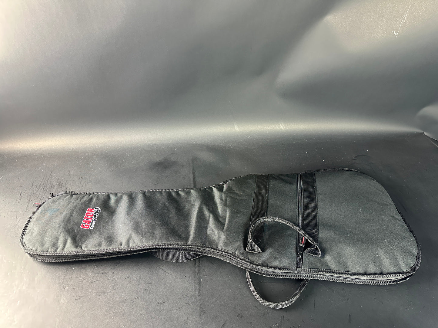 Gray guitar case with a brand logo on a gray background