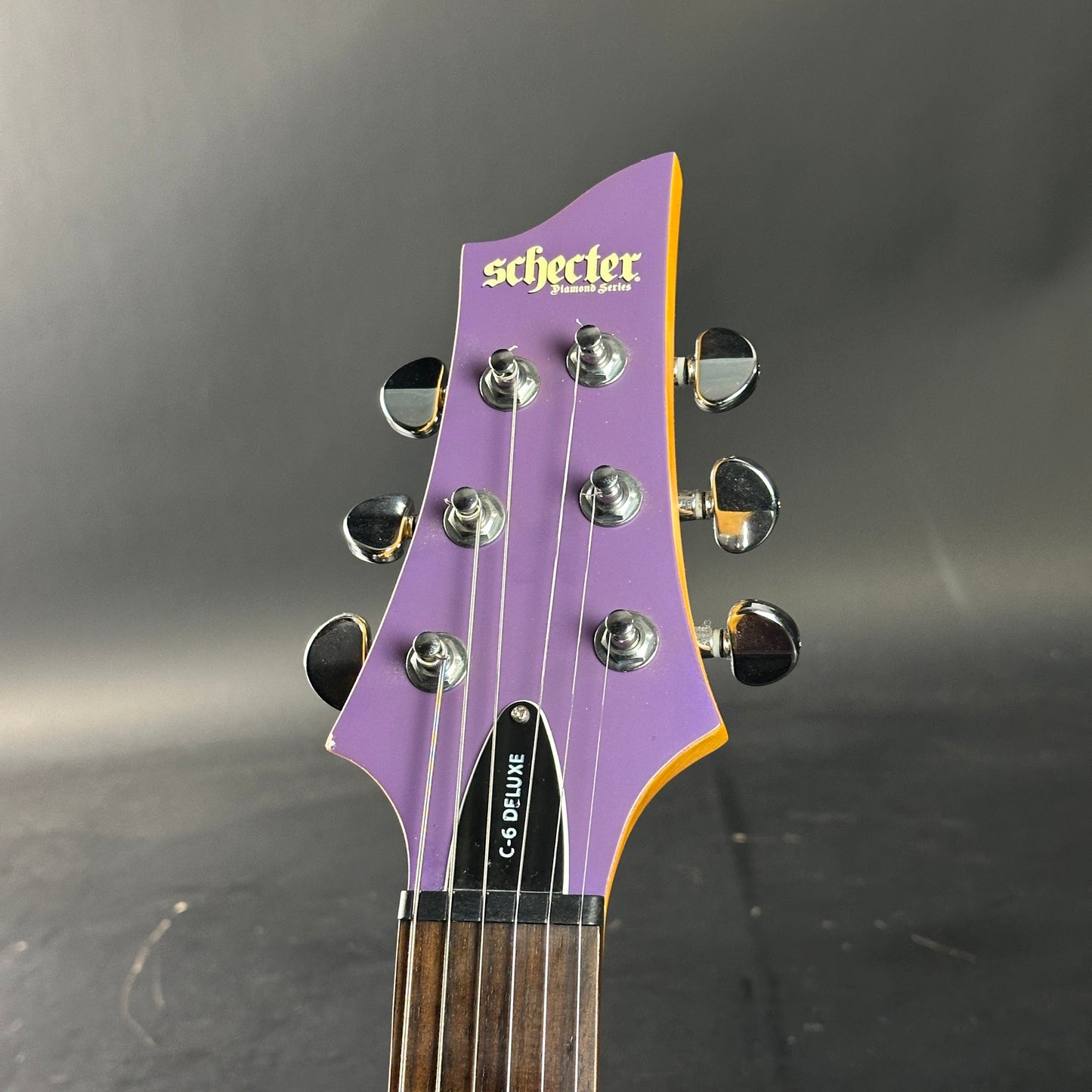 Guitar headstock with 'Schecter' branding on a dark background