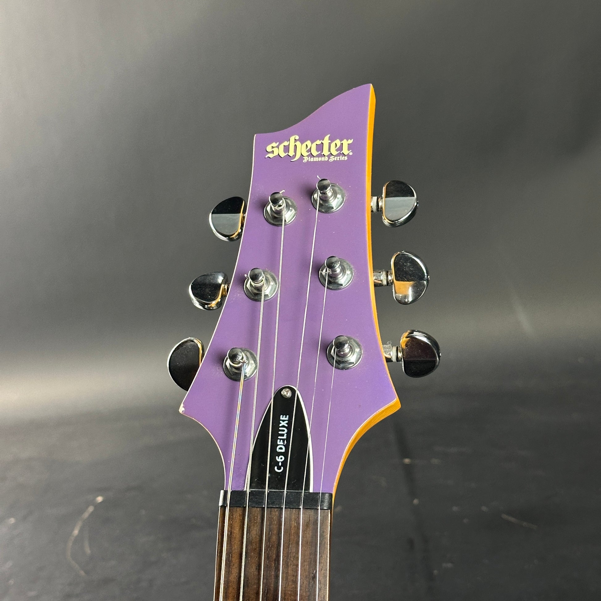 Guitar headstock with 'Schecter' branding on a dark background