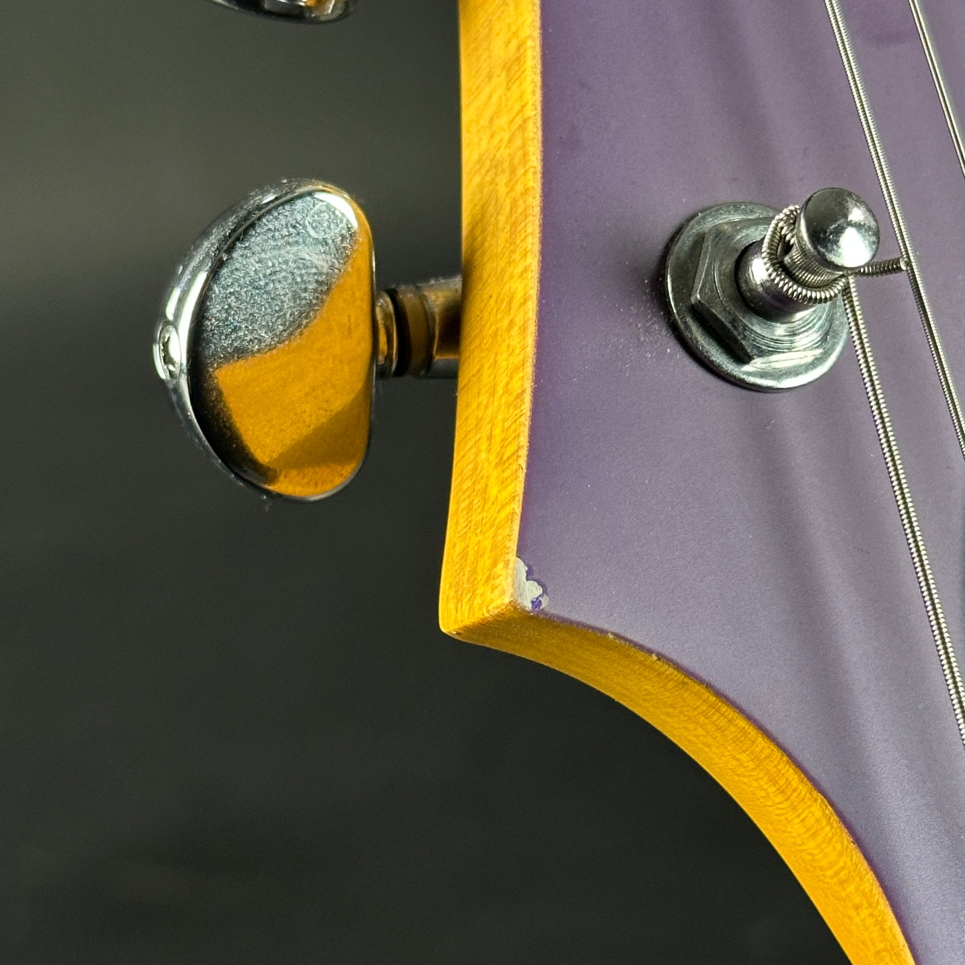 Close-up of a guitar's tuning pegs with a purple and yellow body.