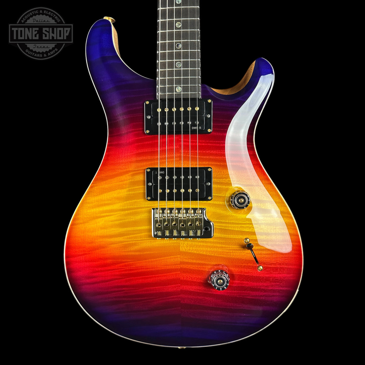 A double-cutaway electric guitar with a vibrant rainbow flame finish transitioning from purple and blue at the top to orange and red at the bottom, shown against a solid black background.