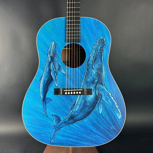 Blue acoustic guitar with whale design on a dark background