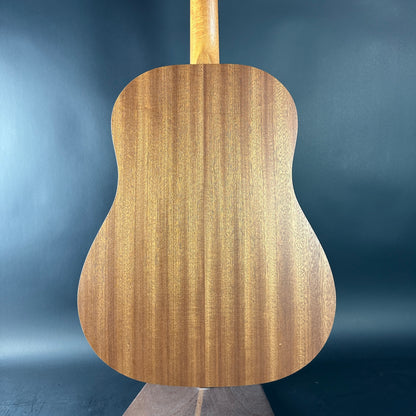 Back view of a wooden acoustic guitar against a blue gradient background