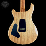 The back of an electric guitar with a natural wood grain finish, black pickguards, and a black plate, shown against a solid black background with a Tone Shop watermark in the top left.