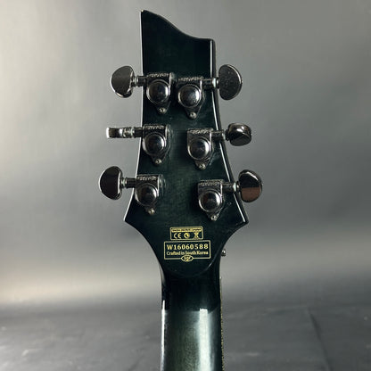 Close-up of a guitar headstock with tuning pegs on a gray background