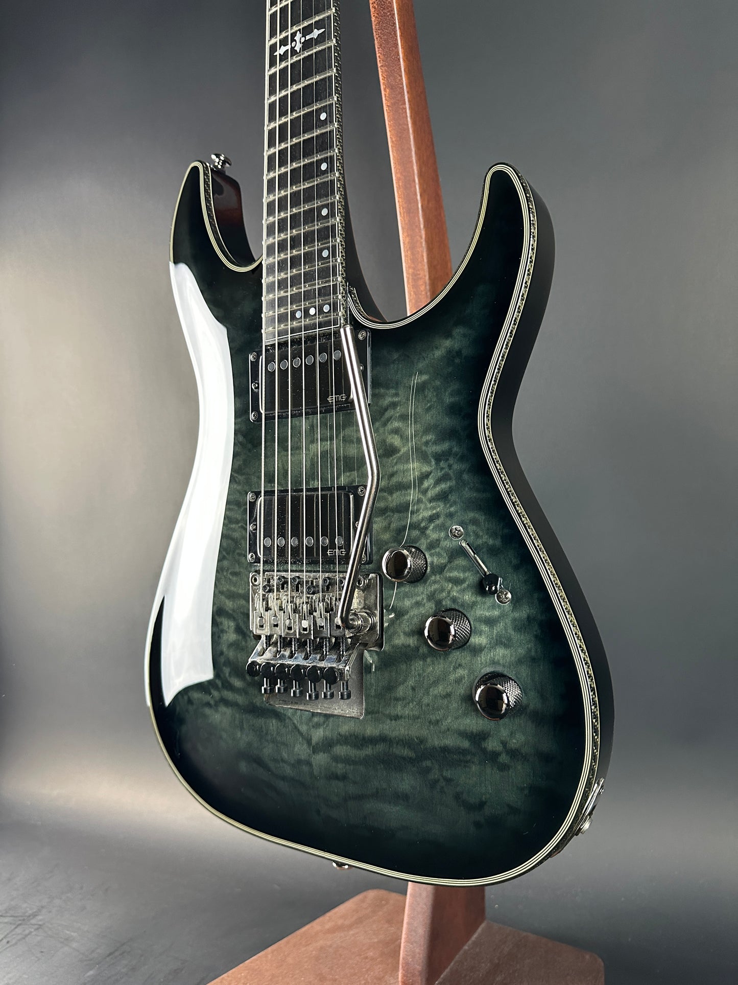 Close-up of a guitar with a dark, textured finish on a gray background