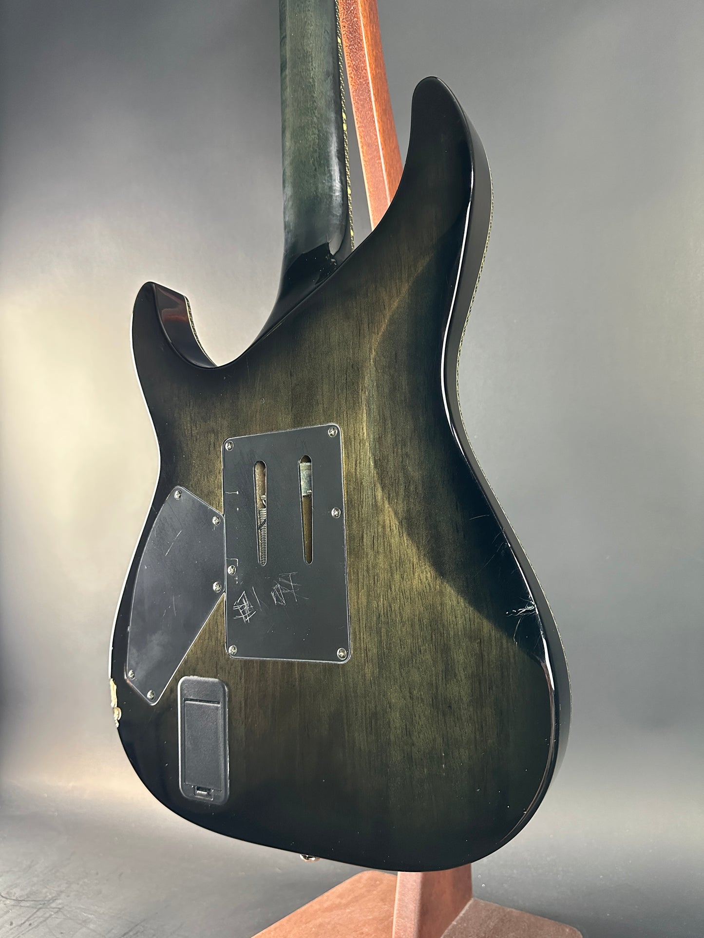 Guitar body with a focus on the back and bridge area against a neutral background