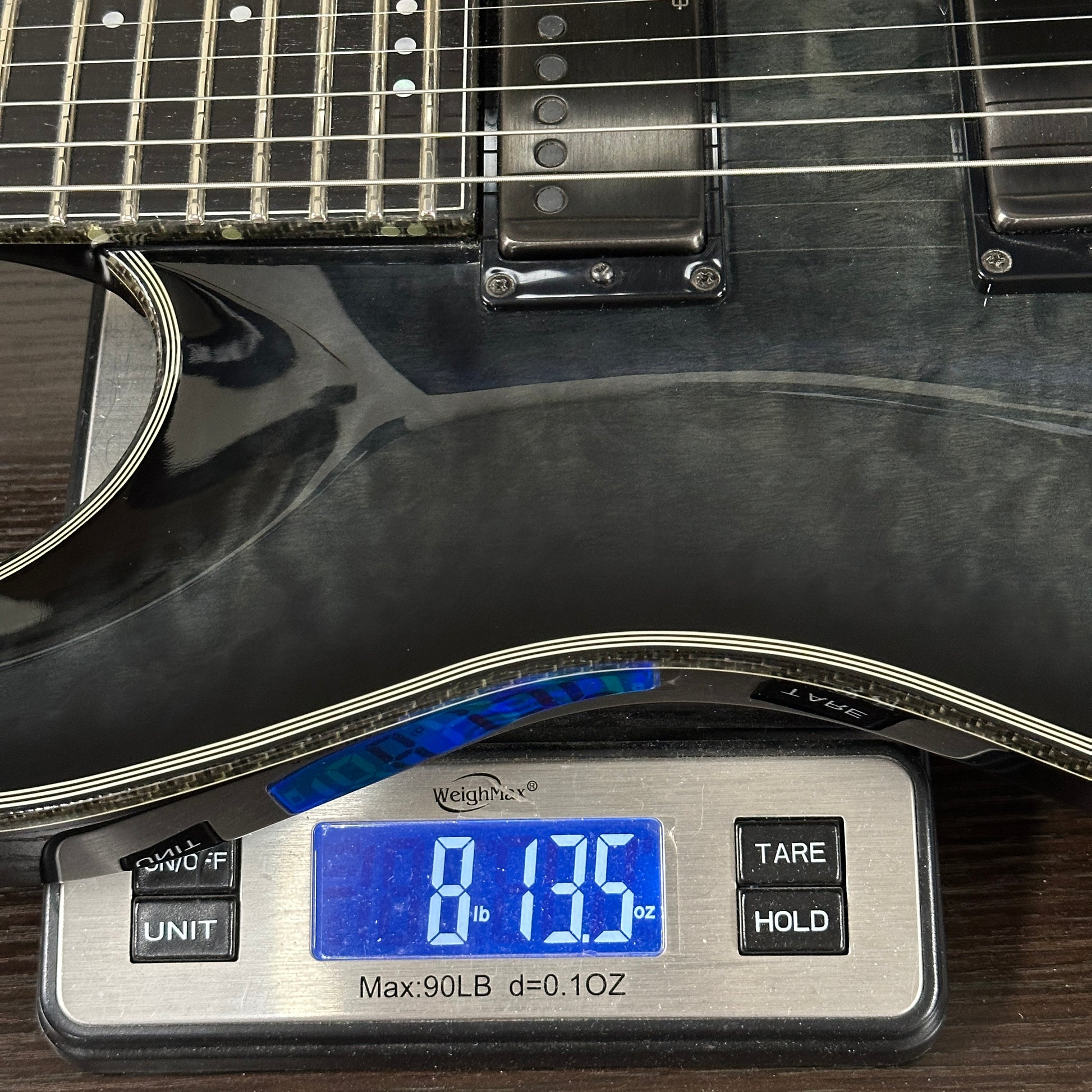 Guitar being weighed on a digital scale with a clear display.
