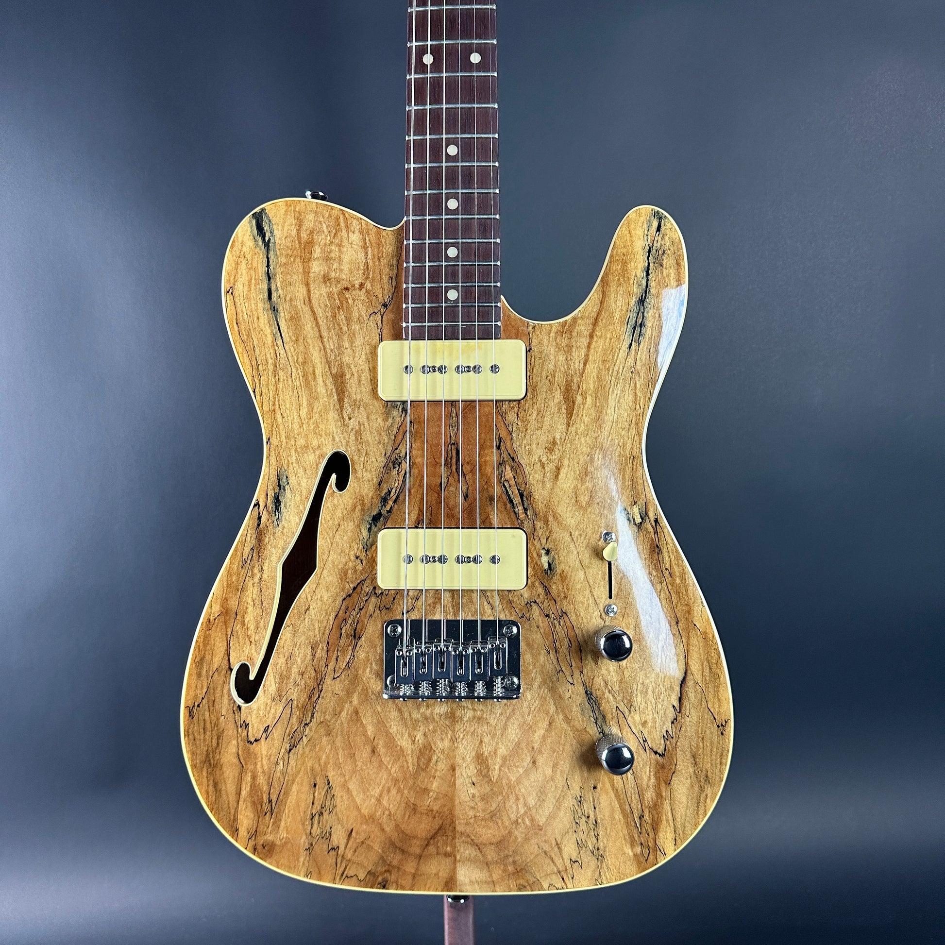 Wooden electric guitar with a marbled pattern on a dark background