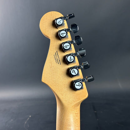 Guitar headstock with tuning pegs on a dark background