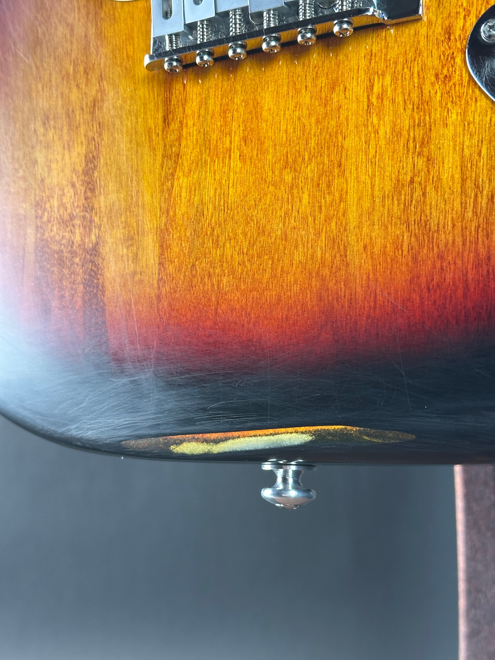 Close-up of a guitar's neck and headstock with a gradient finish.