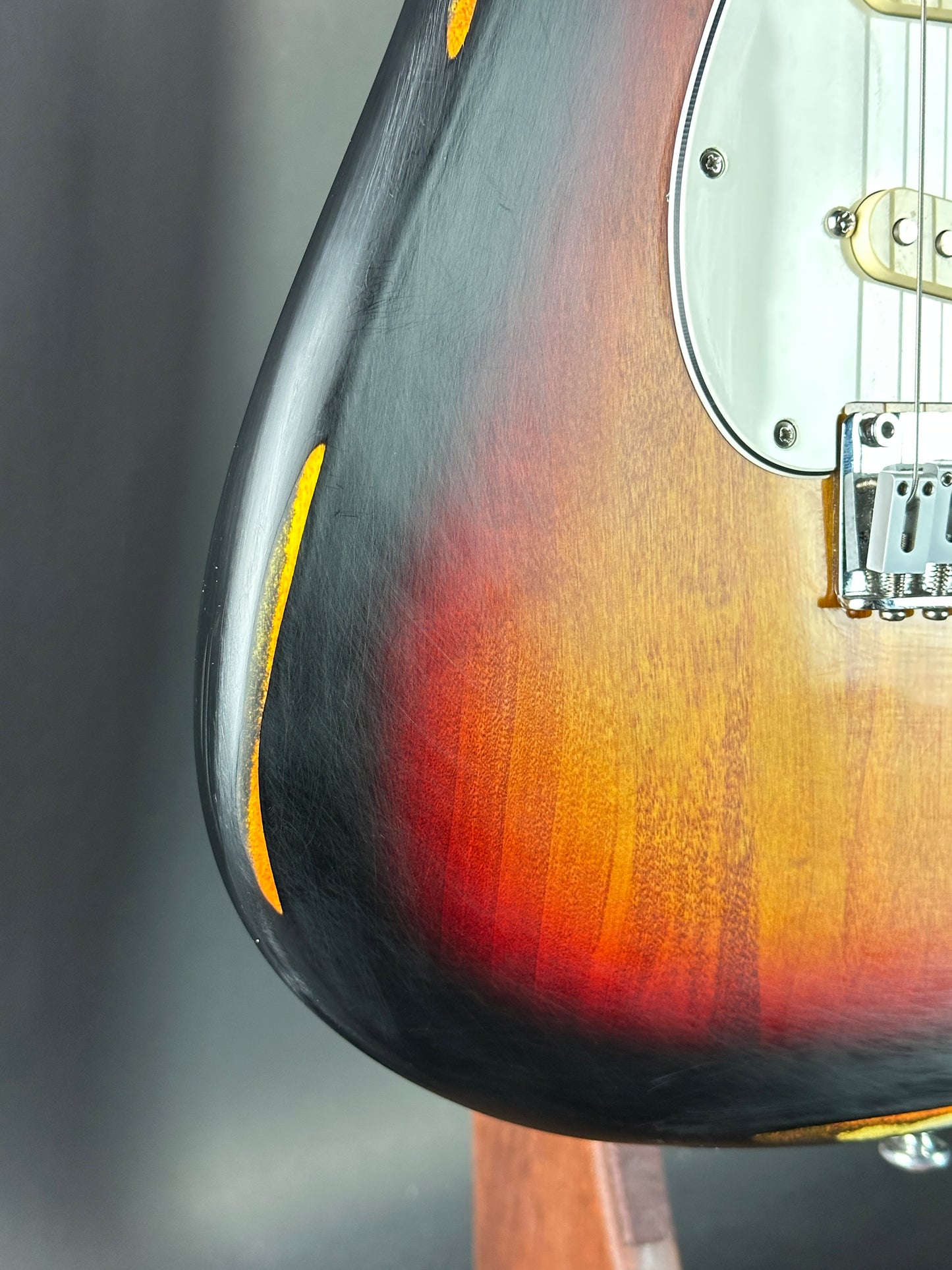 Close-up of a guitar's body with a gradient finish on a gray background