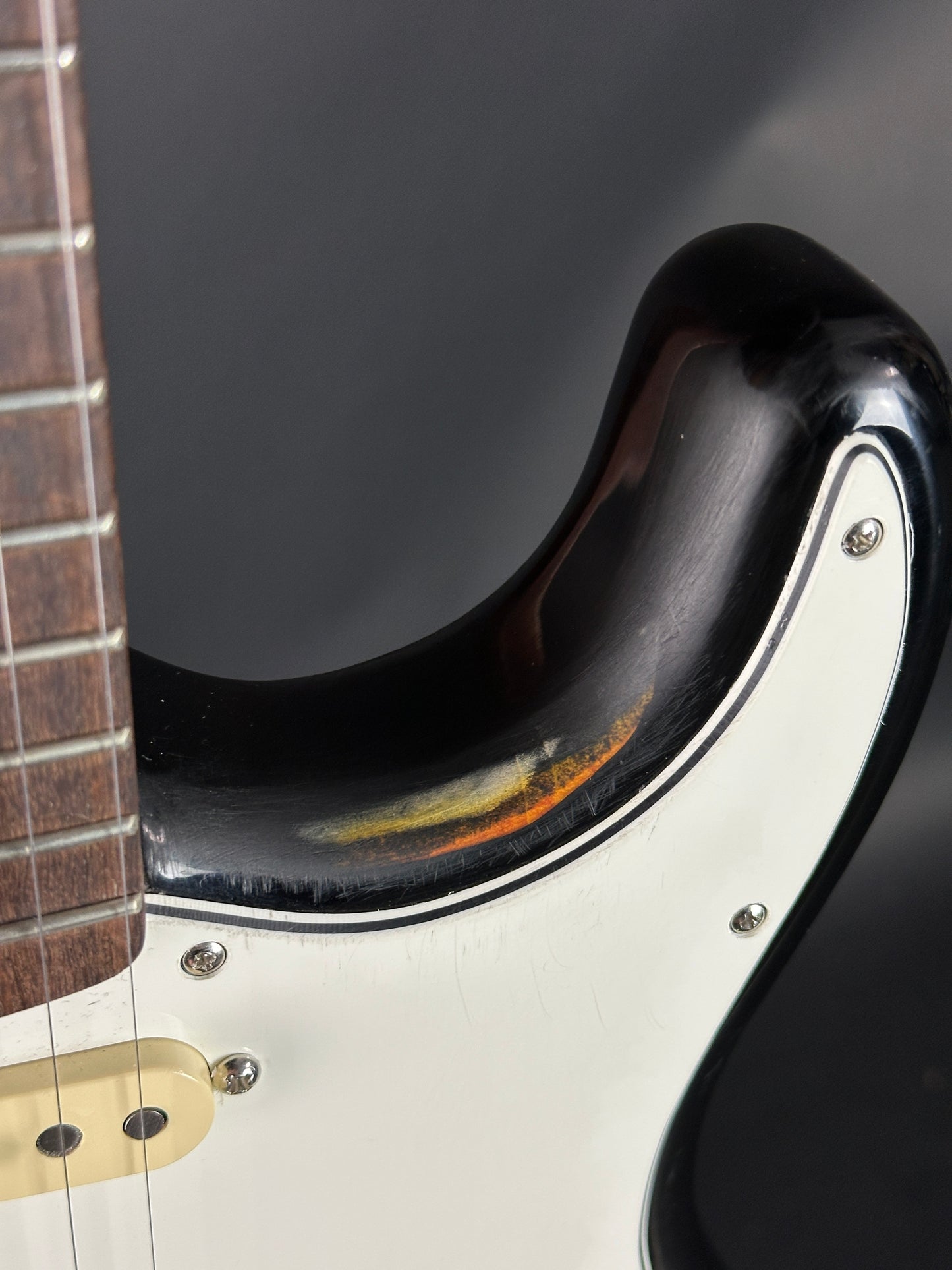 Close-up of a guitar's neck and headstock with a dark finish.