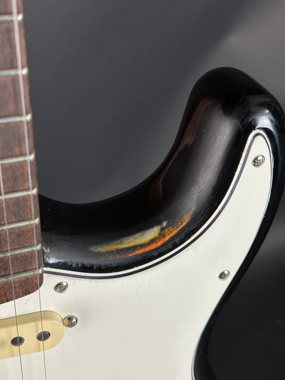 Close-up of a guitar's neck and headstock with a dark finish.