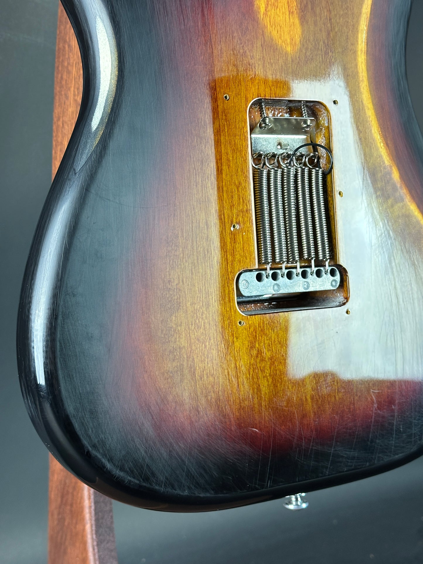 Close-up of a guitar's bridge and pickups with a gradient finish.