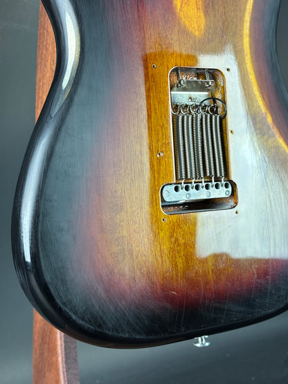 Close-up of a guitar's bridge and pickups with a gradient finish.