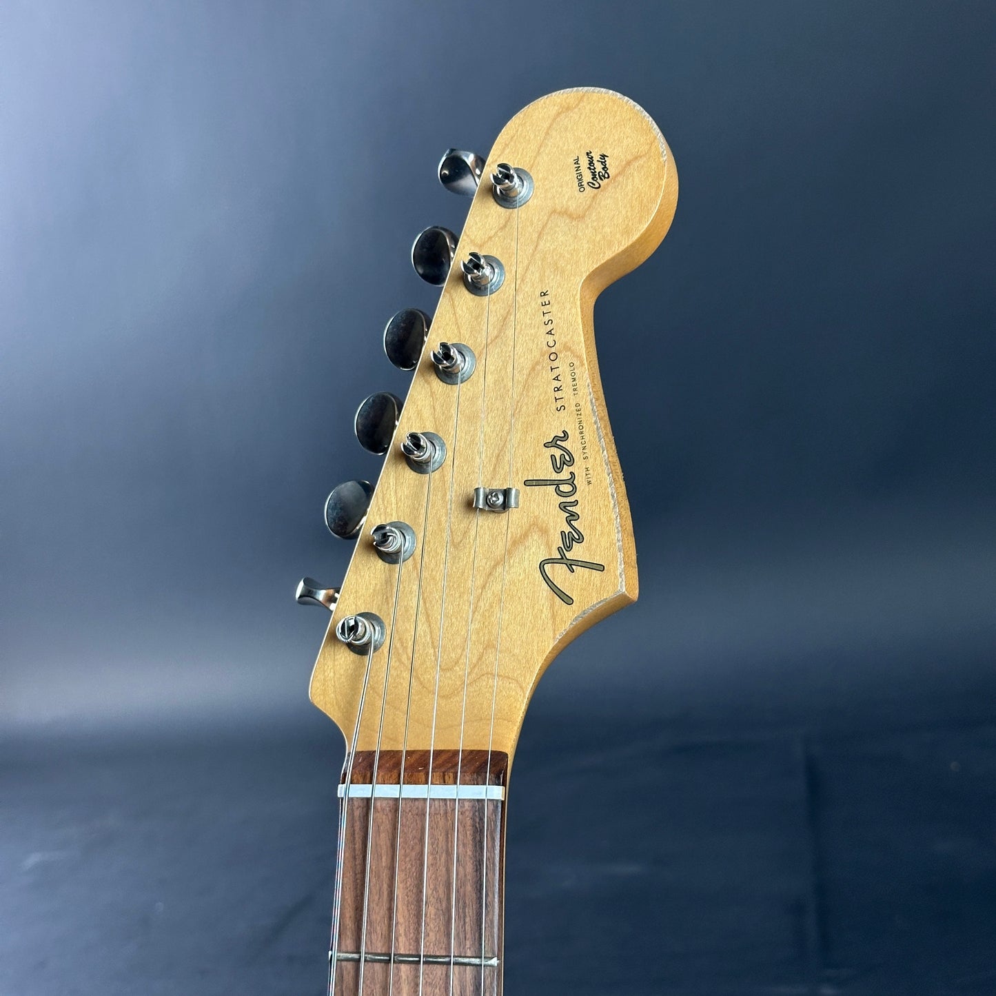 Guitar headstock with Fender logo on a dark background