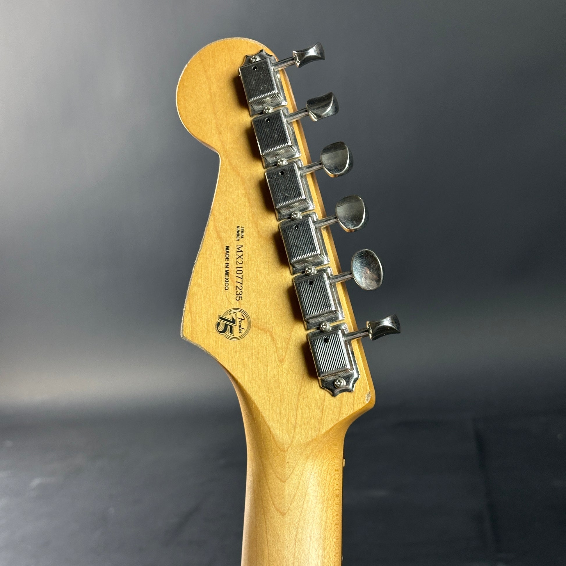 Close-up of a guitar headstock with tuning pegs on a dark background