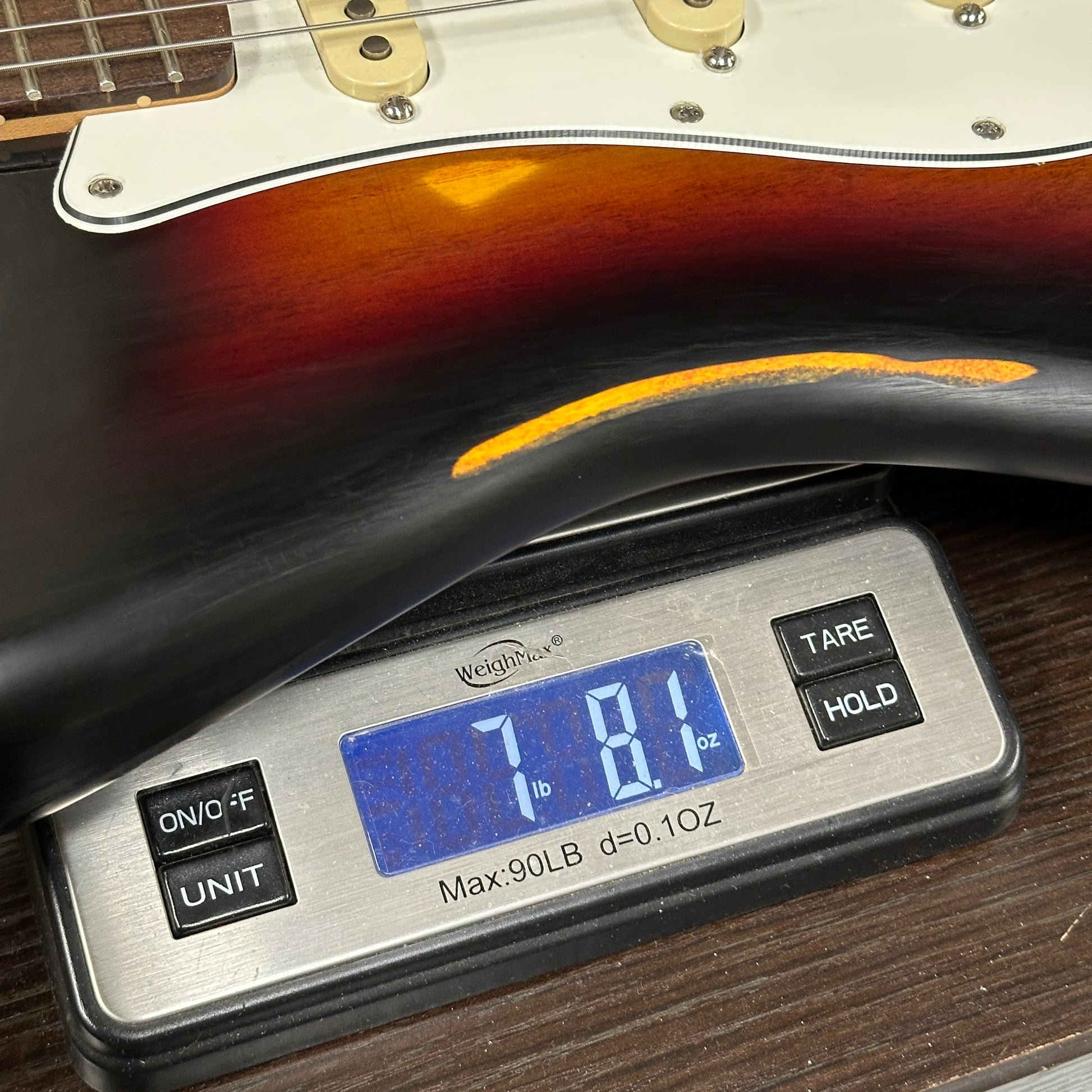 Digital scale displaying weight of a guitar on a wooden surface