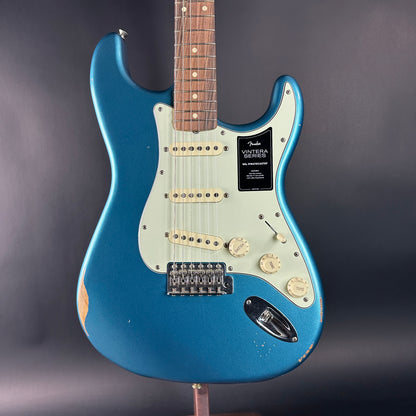 Blue electric guitar on a stand against a dark background