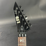 Guitar headstock with brand logo on a dark background