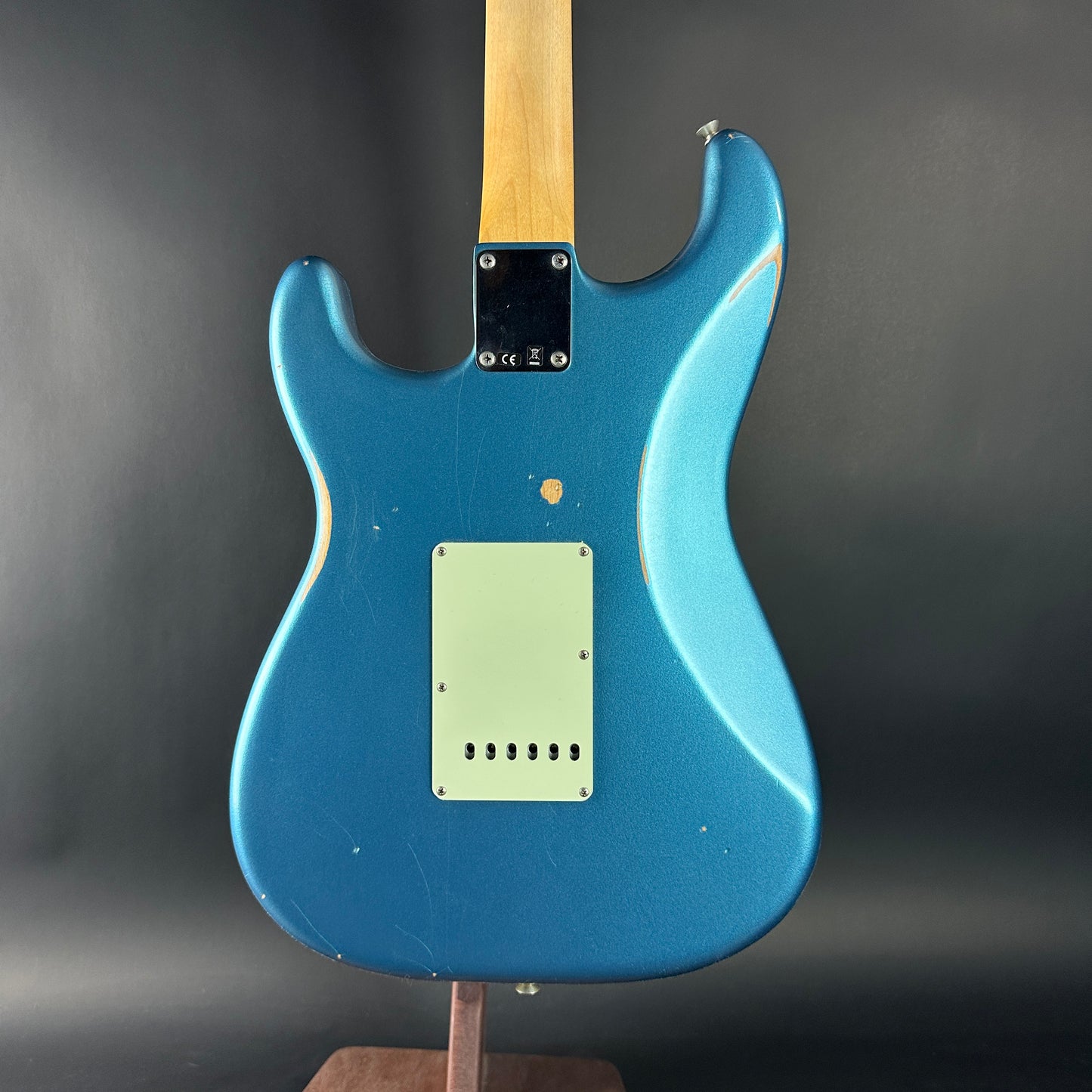 Blue electric guitar on a stand against a dark background