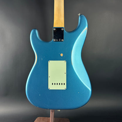 Blue electric guitar on a stand against a dark background
