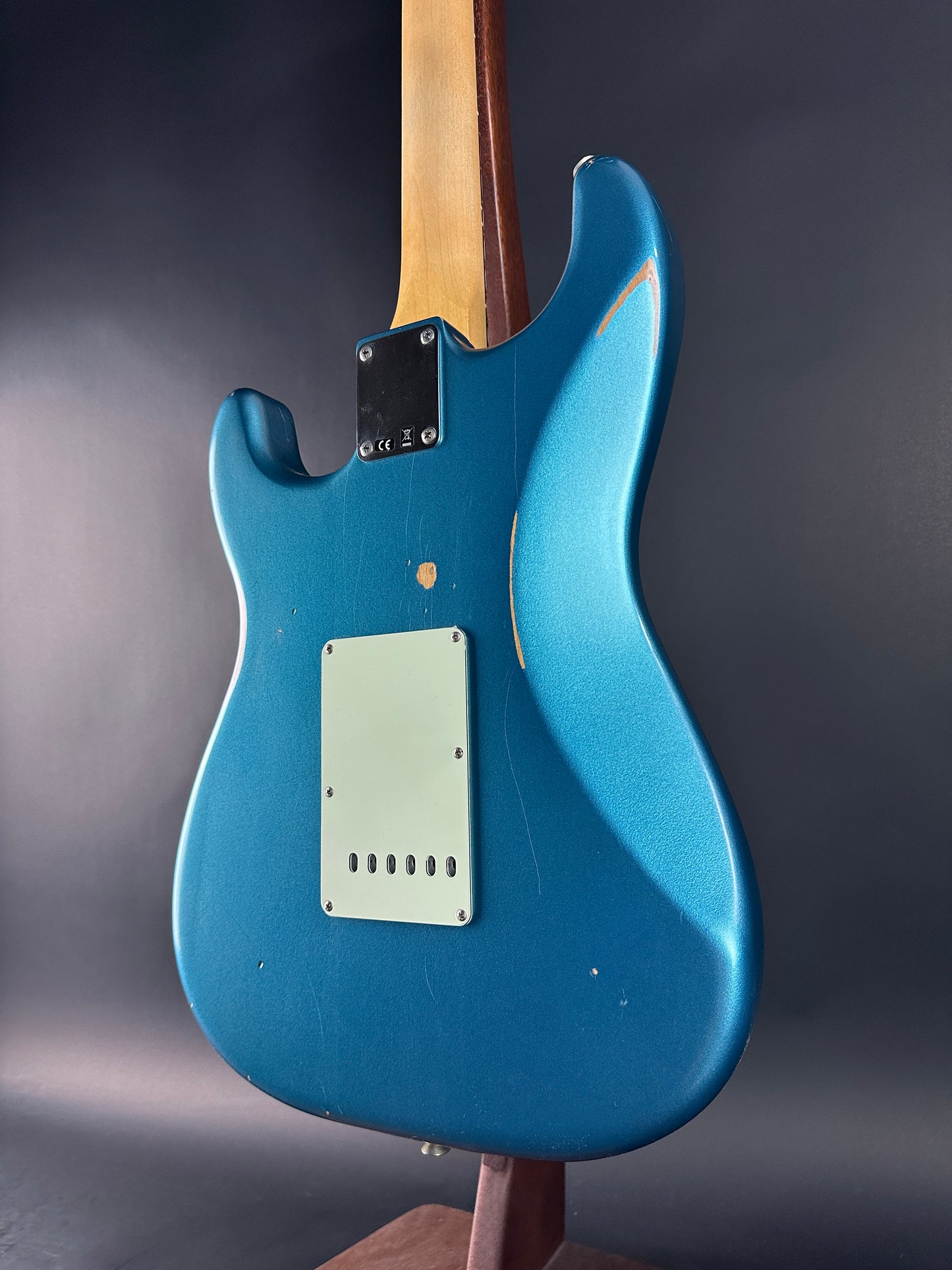 Blue electric guitar with a wooden neck on a dark gray background