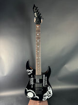 Black electric guitar with white designs on a gray background