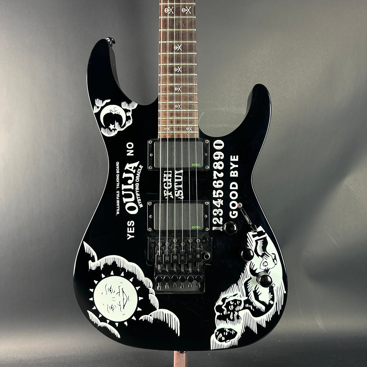 Black electric guitar with white designs and text on a gray background
