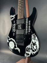 Black electric guitar with white designs on a gray surface