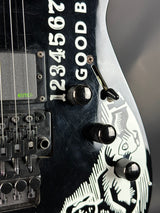 Close-up of a black electric guitar with white text and design