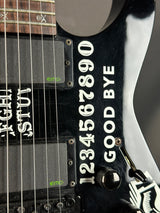 Close-up of a black electric guitar with white text on the body.
