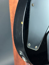 Close-up of a guitar with a black pickguard and wooden body.