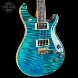A close-up of an electric guitar with a vibrant turquoise and blue flamed maple top, featuring gold hardware and a dark fretboard, set against a solid black background.