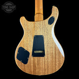 The back of an electric guitar with a natural wood finish and black pickguard, shown against a solid black background with a Tone Shop watermark in the top left corner.