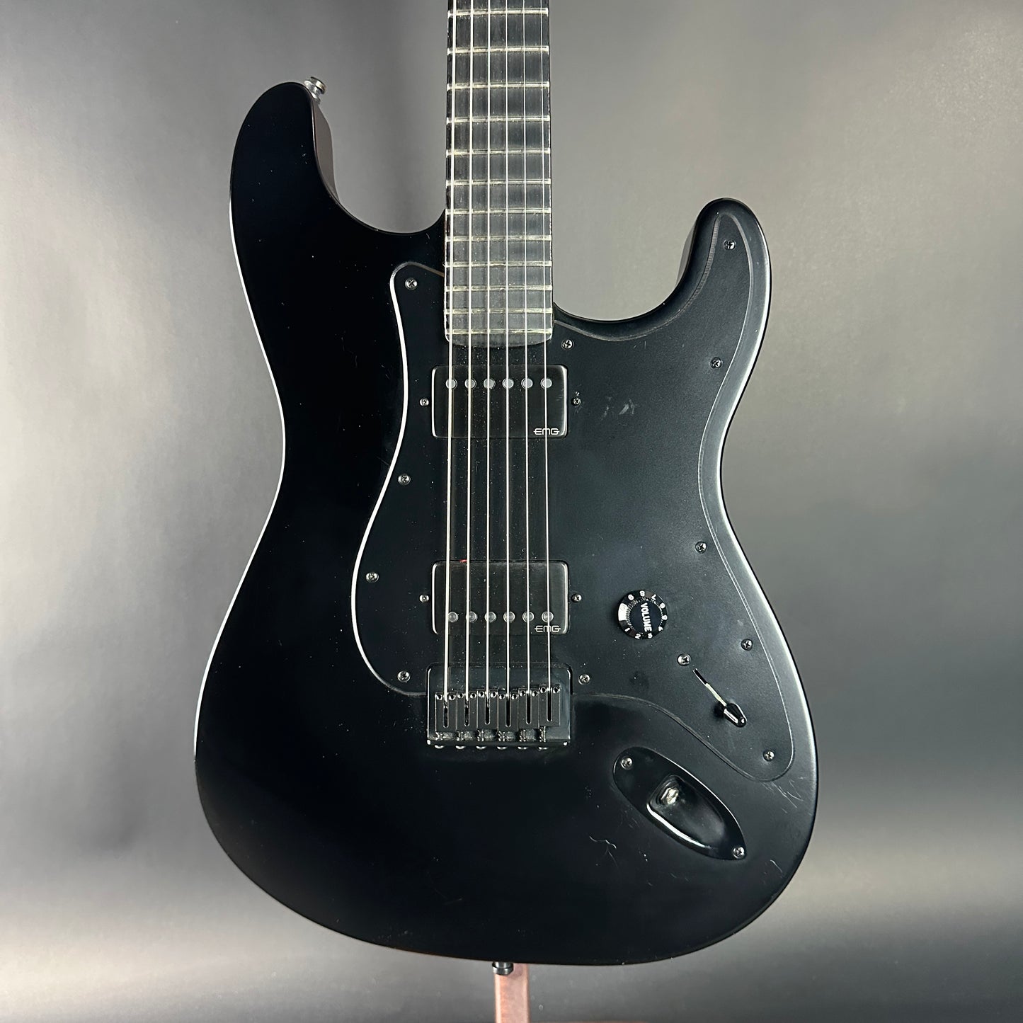 Black electric guitar on a gray background