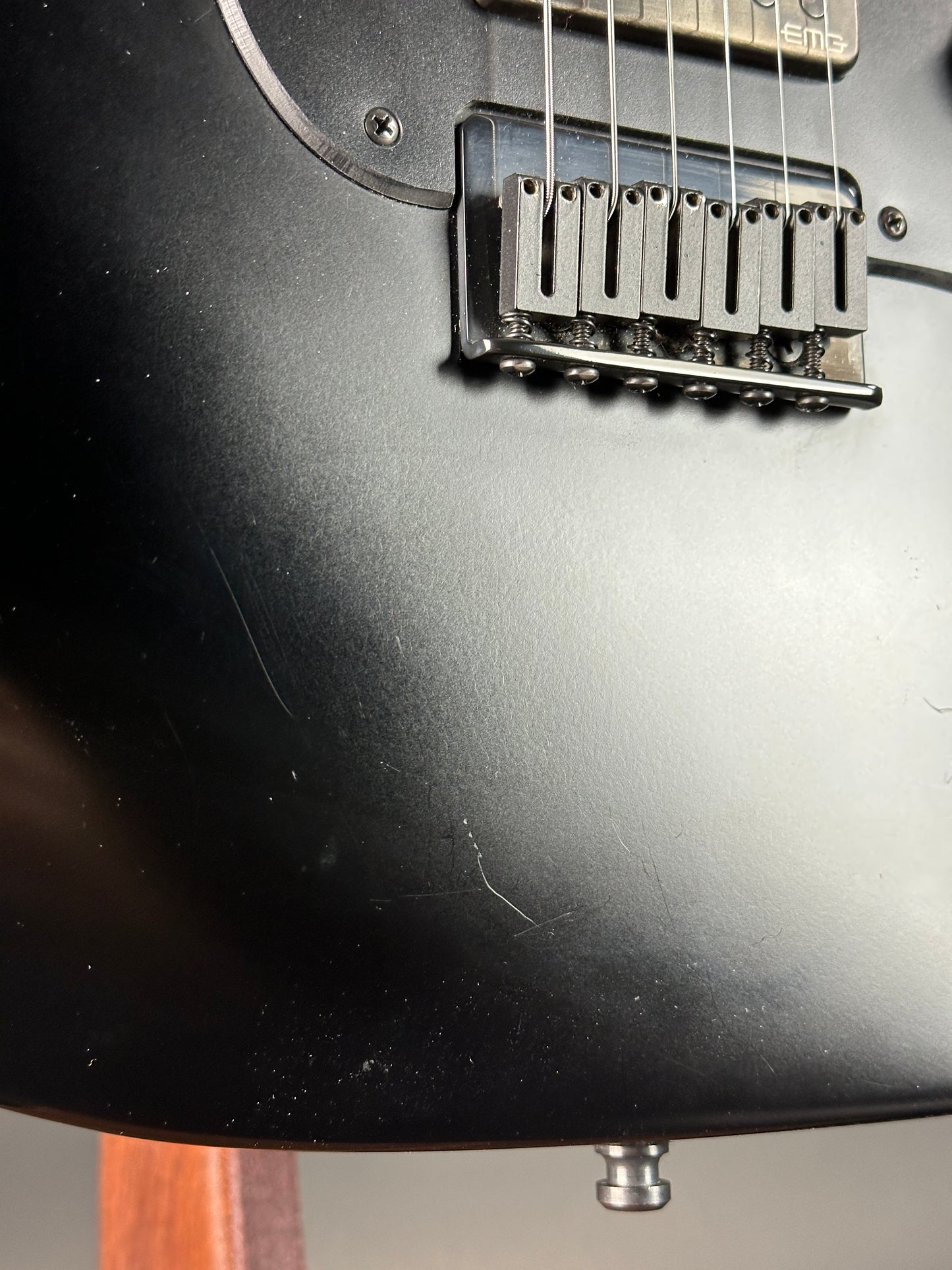 Close-up of a black electric guitar with a focus on the bridge and strings.
