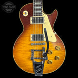 A Gibson Les Paul Custom electric guitar with a natural flame maple body, cream pickguard, and a black Tremolo tailpiece, shown against a solid black background with a Tone Shop watermark in the top left corner.