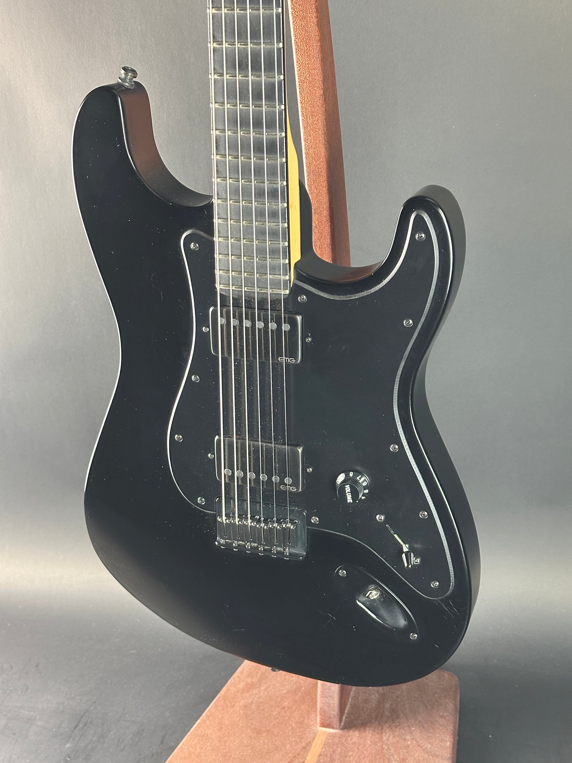 Black electric guitar on a reflective surface with a neutral background