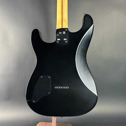 Black electric guitar on a stand with a gray background