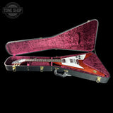 An electric guitar inside an open hard case with a textured magenta-pink velvet interior, shown against a solid black background. A Tone Shop watermark is visible in the top-left corner.
