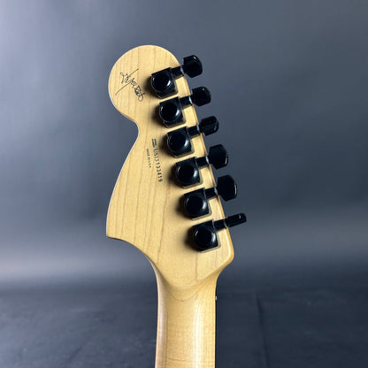 Guitar headstock with tuning pegs on a gray background