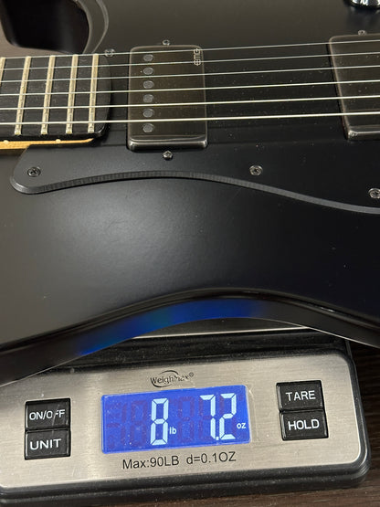 Black electric guitar on a digital scale displaying weight