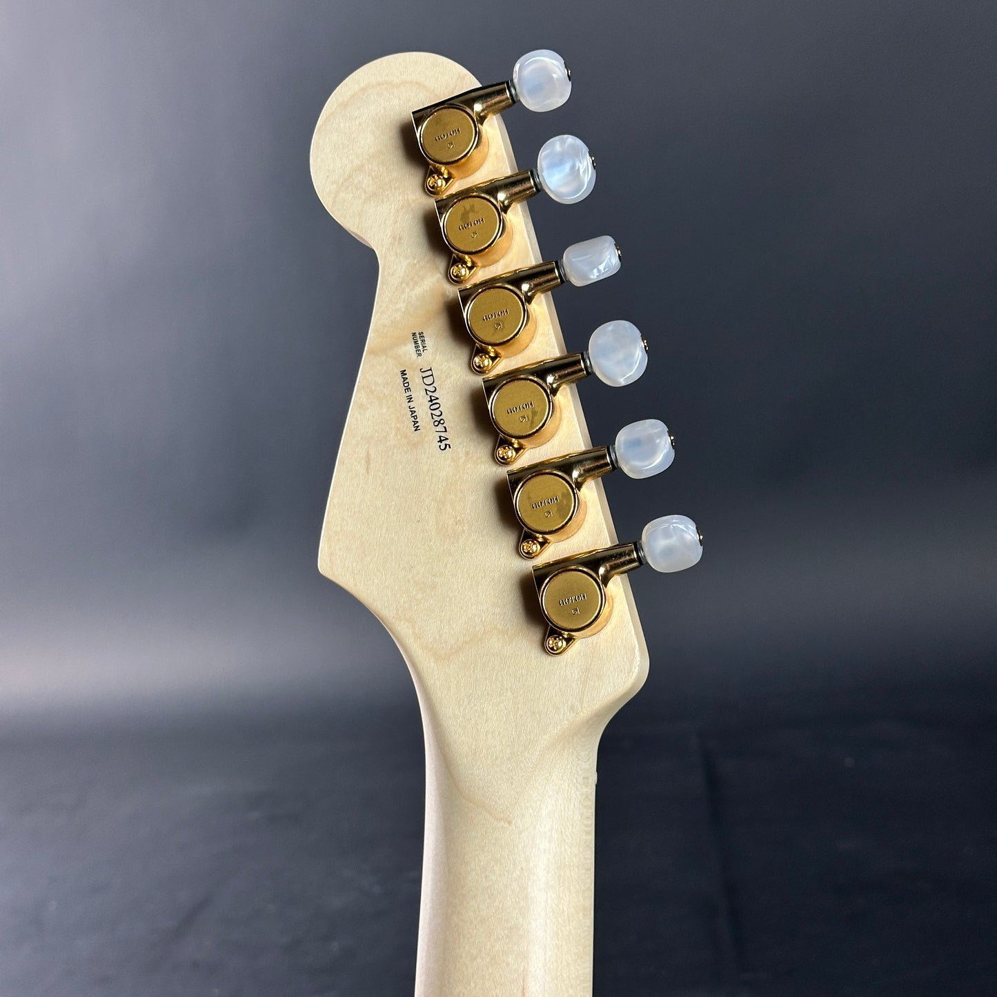 Guitar headstock with tuning pegs on a dark gray background
