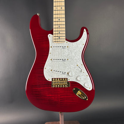 Red electric guitar with a white pickguard on a gray background