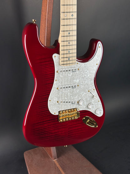 Red electric guitar with a white pickguard on a dark background