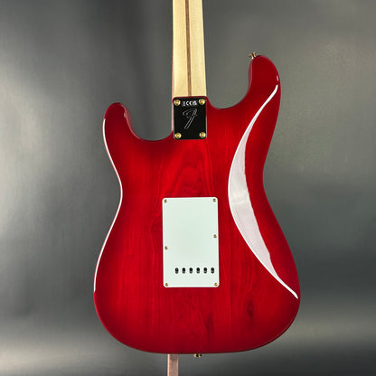 Red electric guitar with a white pickguard on a gray background
