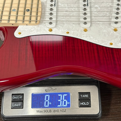 Red electric guitar on a digital scale displaying weight